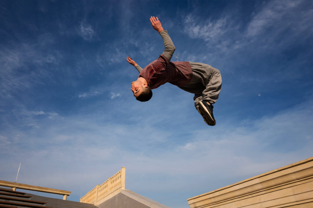 Jongen springt in de lucht en maakt een salto achterover.