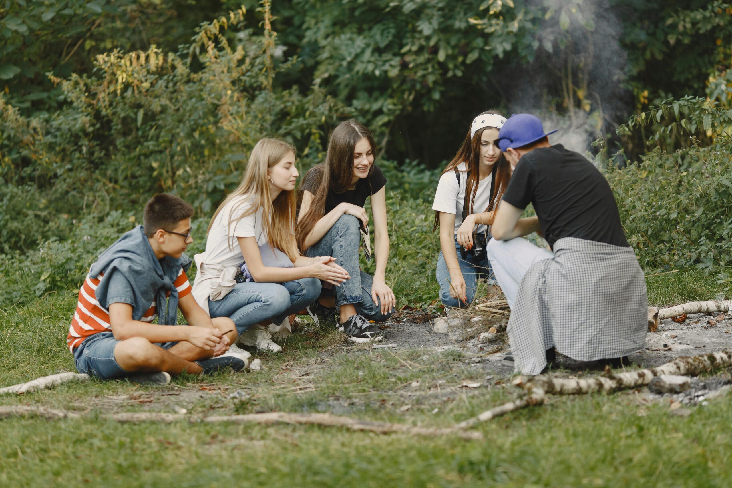Tieners zitten bij elkaar op het gras, in vakantiesetting.